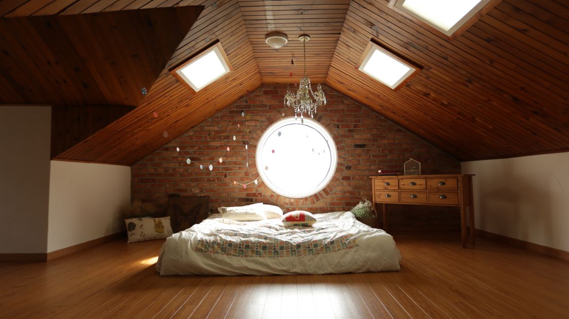 Warm loft conversion bedroom with brick wall and timber ceiling in Leatherhead